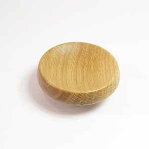 May include: A small, round wooden bowl made of light brown oak wood. The bowl is smooth and has a natural wood grain.