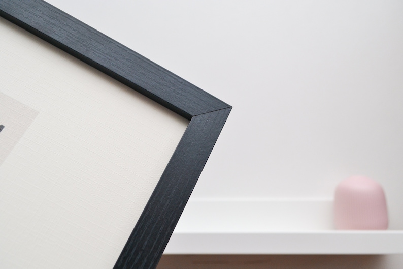 May include: Close-up of a black picture frame with a white mat. The frame is made of wood and has a simple, modern design.