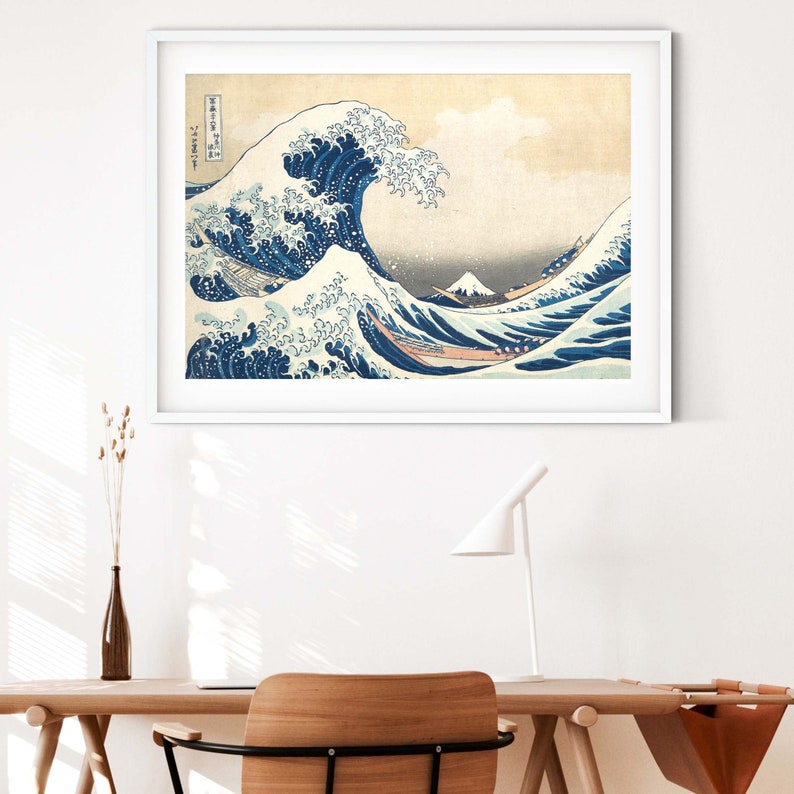 May include: A framed print of a famous Japanese woodblock print depicting a large wave crashing over a boat with Mount Fuji in the background. The print is in shades of blue, white, and gray.