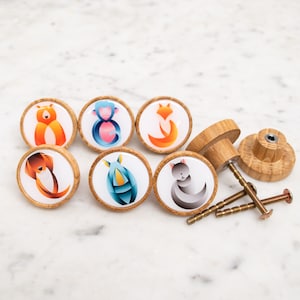 May include: Set of seven wooden knobs with colorful animal illustrations. The knobs are round and have a smooth, polished finish. The animals include a fox, a monkey, a dog, a cat, and a rhino.
