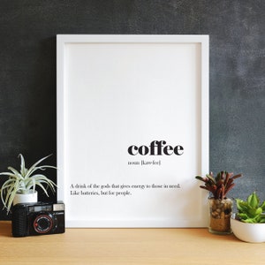 Op de afbeelding: Een wit ingelijst print met zwarte tekst die "coffee noun [kaw-fee] A drink of the gods that gives energy to those in need. Like batteries, but for people." luidt.