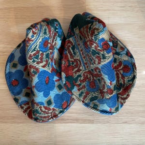 May include: Two blue, red, and green patterned fabric hats. The hats are made of corduroy and have a floral design.
