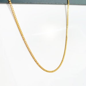 Könnte beinhalten: Eine goldene Halskette mit einem Gliederketten-Stil.