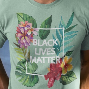 May include: A green t-shirt with a floral print and the text "Black Lives Matter" in a white box.