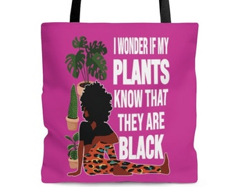May include: A pink tote bag with a black handle and a graphic of a woman with plants. The text on the bag reads "I wonder if my plants know that they are black."