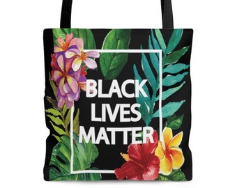 May include: Black tote bag with a floral design and the text "BLACK LIVES MATTER" in a white frame. The bag features a black handle and a black background with colorful flowers and green leaves.
