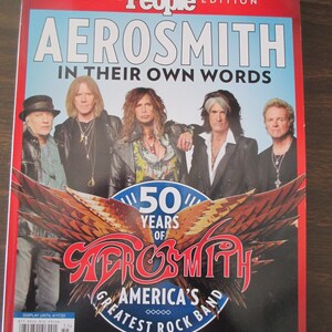 May include: A magazine cover featuring a photo of the rock band Aerosmith. The cover is red with the band's name in white letters and the words "In Their Own Words" in smaller white letters. The band members are all wearing black jackets and are standing in front of a blue sky. The cover also features a logo for the band's 50th anniversary, which includes a large eagle with wings spread out and the words "America's Greatest Rock Band".