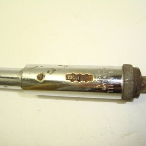 May include: A silver and chrome screwdriver with a metal handle and a black and silver drill bit. The handle has the text "L.S. STARRETT CO. ATHOL MASS. USA" printed on it.