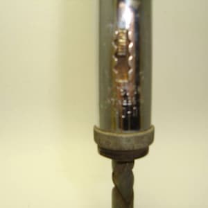 May include: A silver and chrome hand drill with a metal bit. The drill has a textured grip and a metal handle.