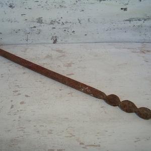 May include: A rusty metal hand drill with a twisted metal shaft and a hook on one end.