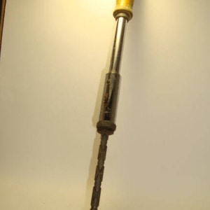 May include: A vintage hand drill with a wooden handle and a metal drill bit. The drill is silver and has a black metal tip.