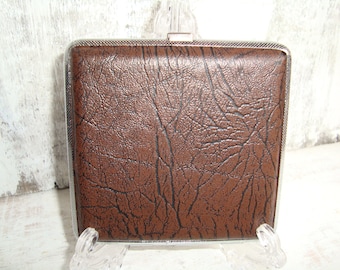 May include: A brown leather cigarette case with a silver metal frame.