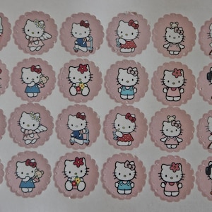 May include: A set of 24 cupcake toppers featuring Hello Kitty in various poses and outfits. The toppers are printed on white paper with pink scalloped edges. The designs include Hello Kitty as a ninja, an angel, a chef, and a musician.