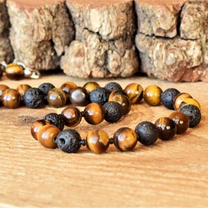 May include: A brown and black beaded necklace with tiger's eye and lava rock beads.