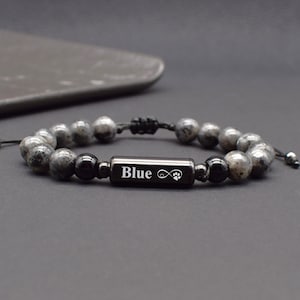May include: Black beaded bracelet with a black metal charm engraved with the word "Blue" and an infinity symbol with a paw print.