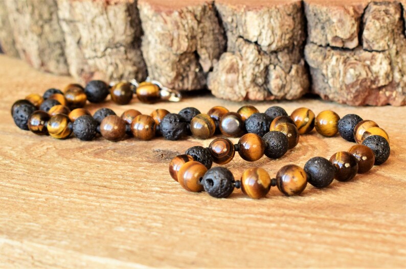 May include: A brown and black beaded necklace with tiger's eye and lava rock beads.