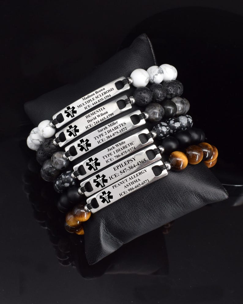 May include: A collection of six medical alert bracelets featuring silver-toned rectangular metal plates engraved with a medical caduceus symbol, names, conditions, and ICE contact numbers, strung with various natural stone beads in white, black, and brown.