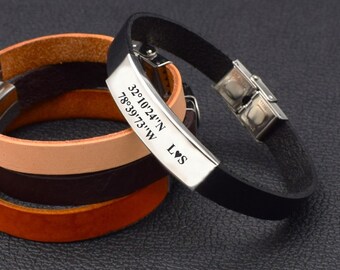 May include: Black leather bracelet with a silver plate engraved with coordinates "32°10'24"N 78°39'73"W" and the letters "L♥S".