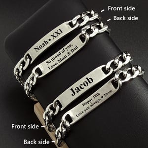 Op de afbeelding: Twee zilverkleurige metalen kettingarmbanden met platte identificatieplaatjes. Eén plaatje is gegraveerd met "Noah • XXI" aan de voorzijde en "So proud of you, Love, Mom & Dad" aan de achterzijde. Het andere plaatje toont "Jacob" en "Happy 18th Love you always, ♥ Mom".