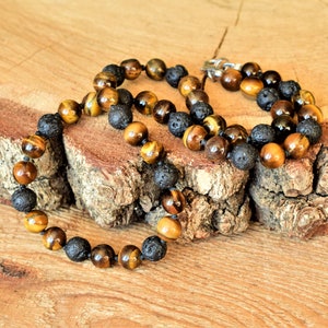 May include: A brown and black beaded necklace with tiger's eye and lava rock beads.