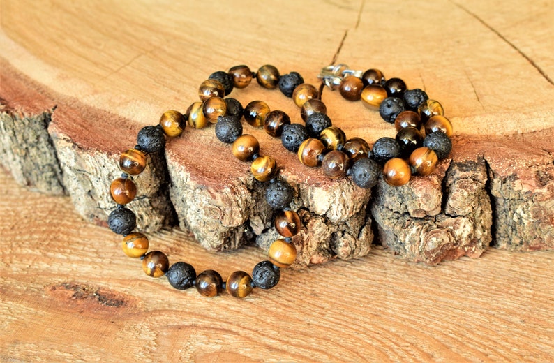 May include: A brown and black beaded necklace with tiger's eye and lava rock beads.