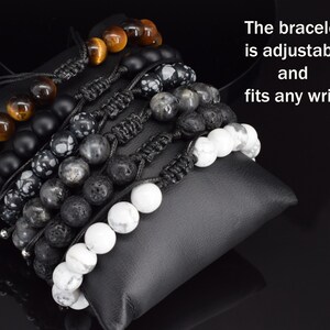 May include: A collection of six adjustable beaded bracelets featuring tiger eye, matte black, snowflake obsidian, grey, lava, and white howlite beads with black cord knots. The text on the image reads: The bracelet is adjustable and fits any wrist.