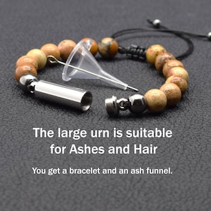 May include: A beaded bracelet with a small metal urn attached. The urn is open and a clear plastic funnel is next to it. The text "The large urn is suitable for Ashes and Hair. You get a bracelet and an ash funnel." is below the image.