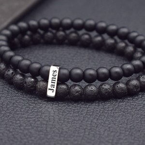 May include: Black beaded bracelet with a silver name tag that reads "James".