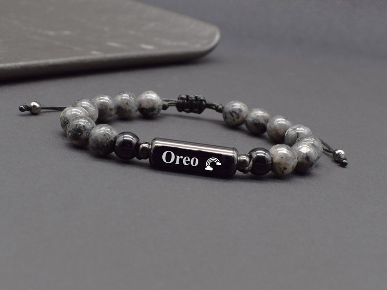 May include: A black beaded bracelet with a black metal bar that says "Oreo" with a rainbow symbol.