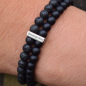 Può includere: Braccialetto con perline nere e un ciondolo argentato con la scritta "Geremia 29:11".