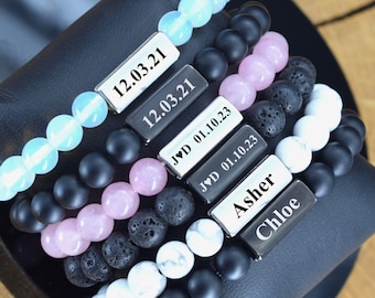 May include: A set of six bracelets with different colored beads and engraved metal tags. The tags include dates, initials, and names like "Asher" and "Chloe".