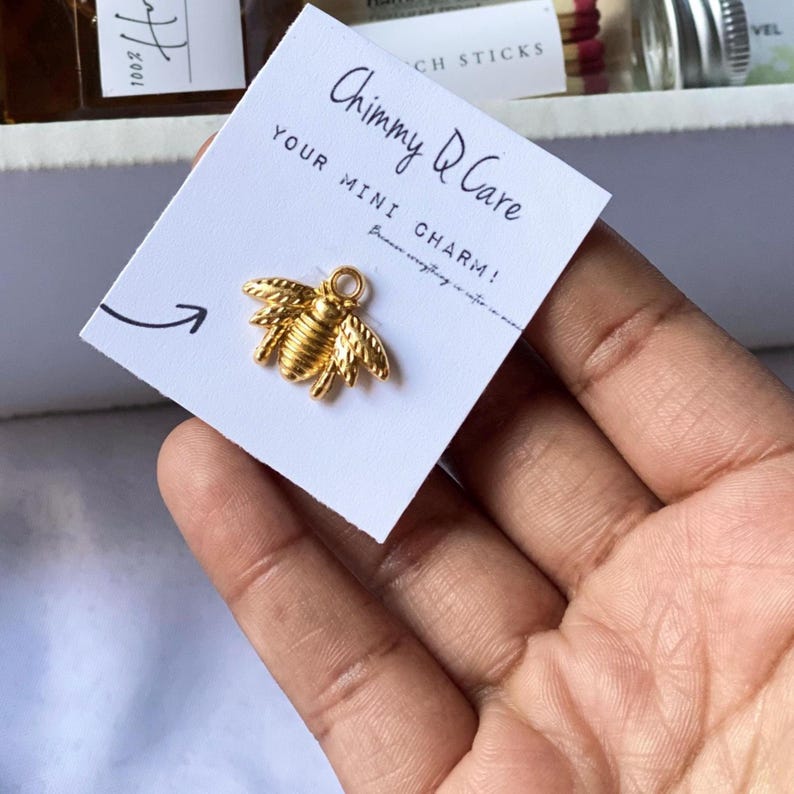 May include: A white card with the text "Chimmy Q Care Your Mini Charm!" and a gold bee charm.