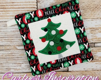 Könnte beinhalten: Ein schwarzer und weißer gesteppter Topflappen mit einem grünen Weihnachtsbaum-Design in der Mitte. Der Rand des Topflappens hat ein sich wiederholendes Muster aus roten und weißen Schneeflocken, Weihnachtslichtern und den Wörtern "Peace", "Joy", "Merry" und "Cheer".