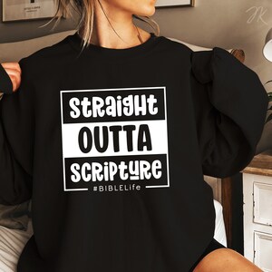 Op de afbeelding: Zwart sweatshirt met witte tekst die "Straight Outta Scripture #BibleLife" zegt.