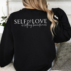 Puede incluir: Sudadera negra con texto blanco que dice "SELF LOVE is setting boundaries".