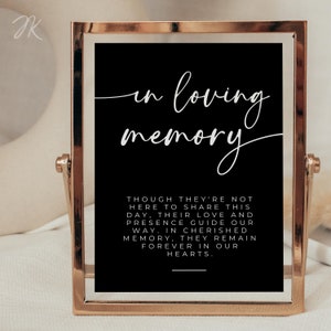 May include: A black framed sign with white text that reads "In loving memory" and a message about remembering loved ones. The sign is on a gold stand.