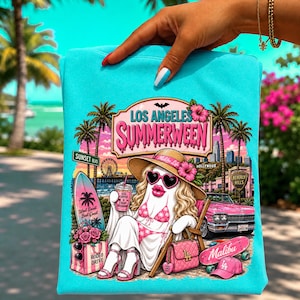 Puede incluir: Una sudadera de color turquesa brillante con un estampado gráfico de un fantasma con sombrero de paja, gafas de sol en forma de corazón y bikini, sentado en una silla de playa. El diseño incluye palmeras, un coche rosa, una tabla de surf y el texto Los Angeles Summerween.