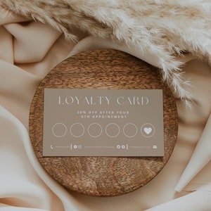 Op de afbeelding: Een bruinachtige klantenkaart met de woorden "LOYALTY CARD" bovenaan. De kaart biedt 20% korting na de 6e afspraak. Er zijn vijf cirkels en een hartsymbool. De kaart ligt op een houten bord.
