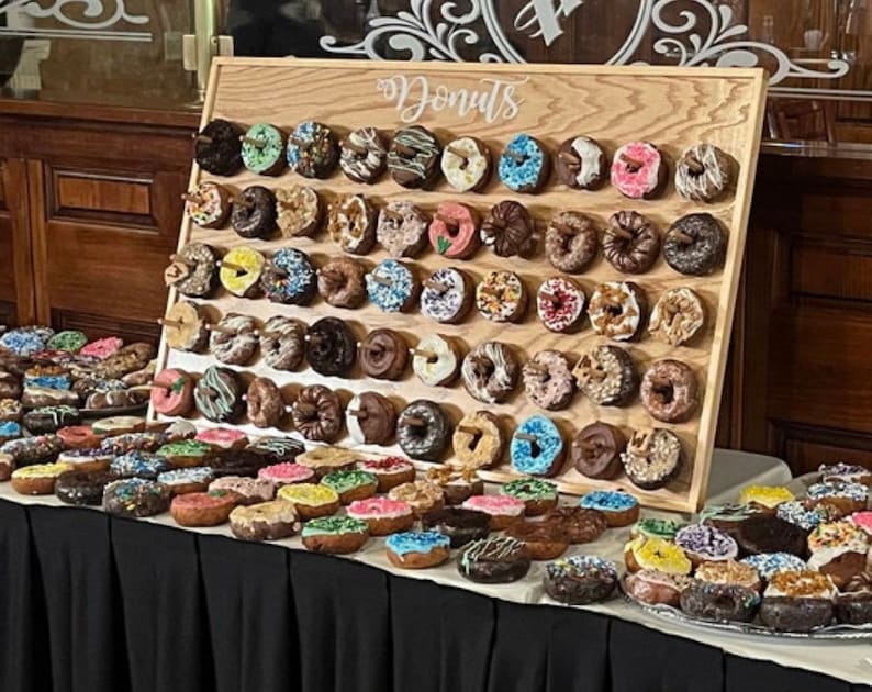 Our Donut walls are sure to be a hit at your next party or event! Each one comes with a stand on the back and has a variety of color choices. It has 30 pegs, and they can be short, that hold 1 donut per peg or long, that hold 2 donuts peg.