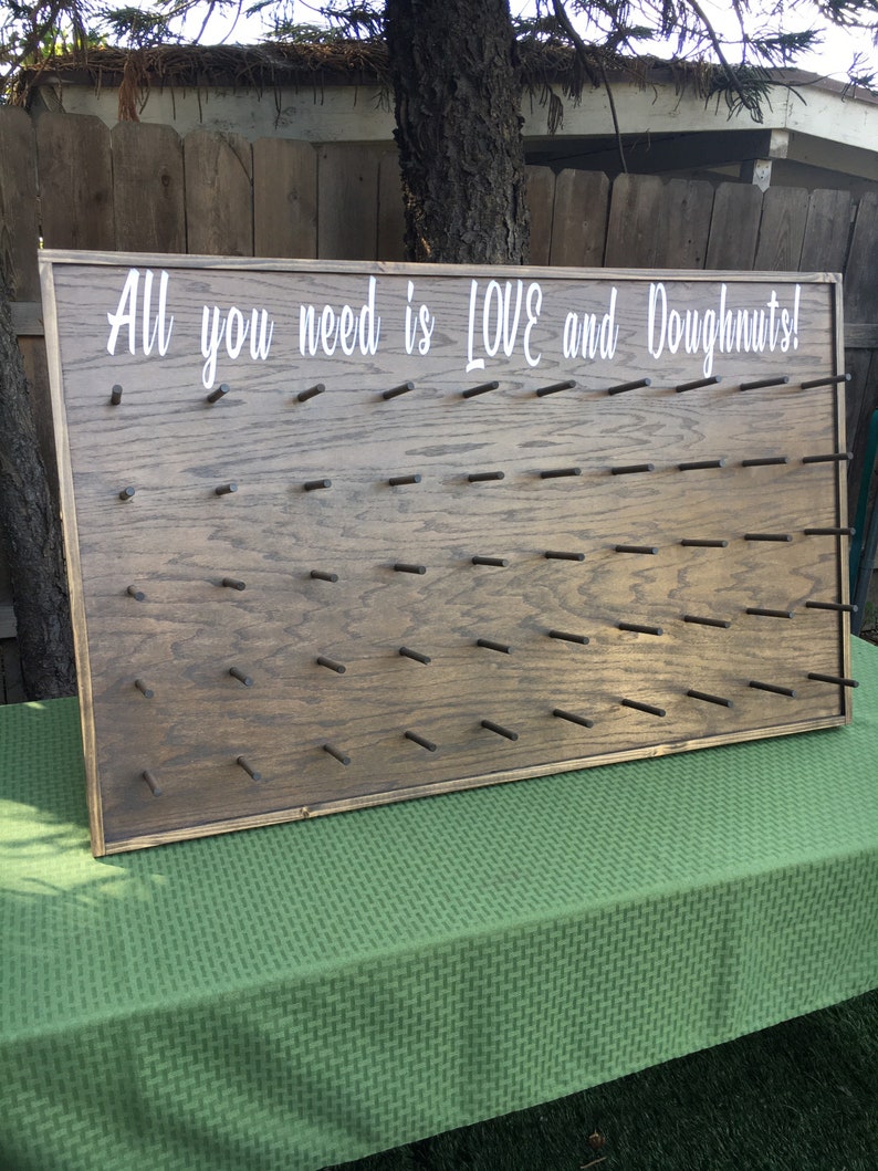 Our Donut walls are sure to be a hit at your next party or event! Each one comes with a stand on the back and has a variety of color choices. It has 30 pegs, and they can be short, that hold 1 donut per peg or long, that hold 2 donuts peg.