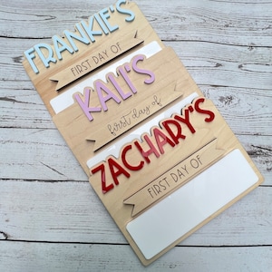 May include: Three wooden signs with the names Frankie, Kali, and Zachary, each with a banner that says "First Day Of". The signs are layered on top of each other, with the top sign being Frankie's and the bottom sign being Zachary's.
