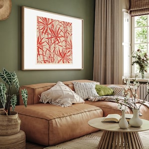 May include: A brown leather sectional sofa with white and black patterned pillows, a green throw pillow, and a striped throw blanket. A small wooden coffee table with a book and two vases with white flowers sits in front of the sofa. The sofa is in a living room with a green wall, a large framed print of red palm leaves, and a window with white blinds.