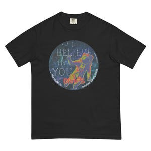 May include: Black t-shirt with a circular graphic featuring an astronaut in a spacesuit against a starry background. The graphic includes the text "I BELIEVE IN YOU" and "BMFS" with the location "Huntsville, AL" and the date "October 23-25, 2023".