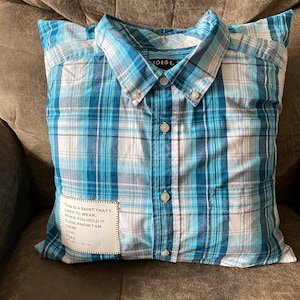 May include: A blue and white plaid pillow with a sewn-on pocket containing a note that reads "THIS IS A SHIRT THAT I LIKED TO WEAR. WHEN YOU HOLD IT CLOSE KNOW I AM THERE. LOVE. PAPA 5/19/15"