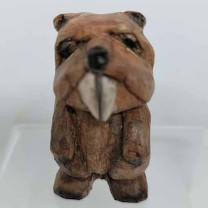 May include: A hand-carved wooden beaver figurine with a brown and tan finish. The beaver has large teeth and a detailed face.
