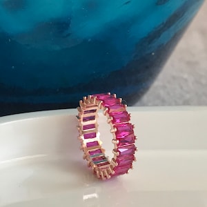 May include: A rose gold ring with a band of pink rectangular stones.