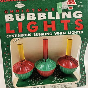 May include: Vintage Christmas bubbling lights set. The box is green with the words "Christmas Bubbling Lights" in red and white. The set includes three lights with red and green bases and yellow and red tubes. The box reads "Glamorize Your Tree".