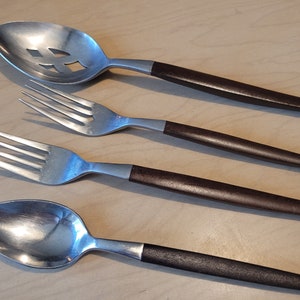 May include: Four pieces of silverware with brown wooden handles. The set includes a slotted spoon, two forks, and a spoon.
