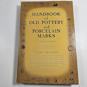May include: A yellow book titled "Handbook of Old Pottery and Porcelain Marks" by C. Jordan Thorn. The book features a foreword by John Meredith Graham II and includes nearly 4,000 marks.