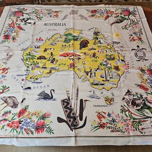 May include: A vintage linen tablecloth featuring a map of Australia in yellow and green, surrounded by colorful floral and fauna illustrations. The word "AUSTRALIA" is printed across the top.